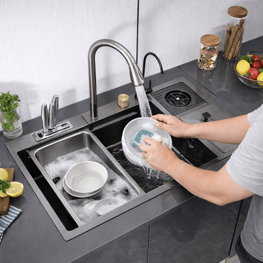 Person washing dishes in a modern kitchen sink with a person partially visible.